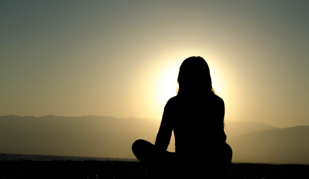 woman thinking in front of a sunrise